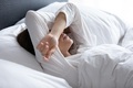 Woman lying with hands on head having difficulty sleeping | istock.com/fizkes