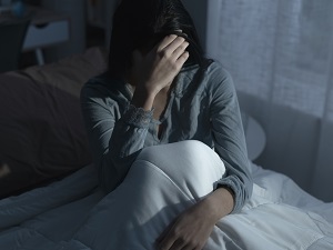 Woman lying in bed late at night suffering from insomnia and feels exhausted. Credit: iStock.com/cyano66