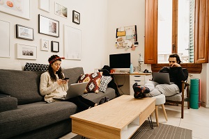 Young couple at home using computers in the living room. Credit: istock.com/FilippoBacci