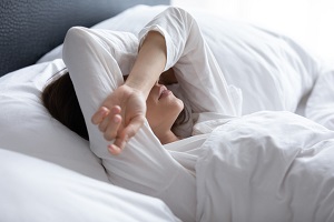 Sleepless young woman covering eyes with hands | istock.com/fizkes